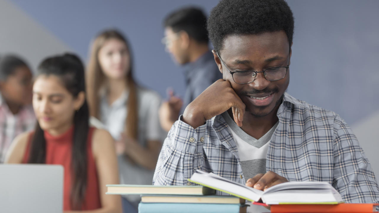 Estudante negro estuda enquanto aguarda a aula começar na sala da universidade 