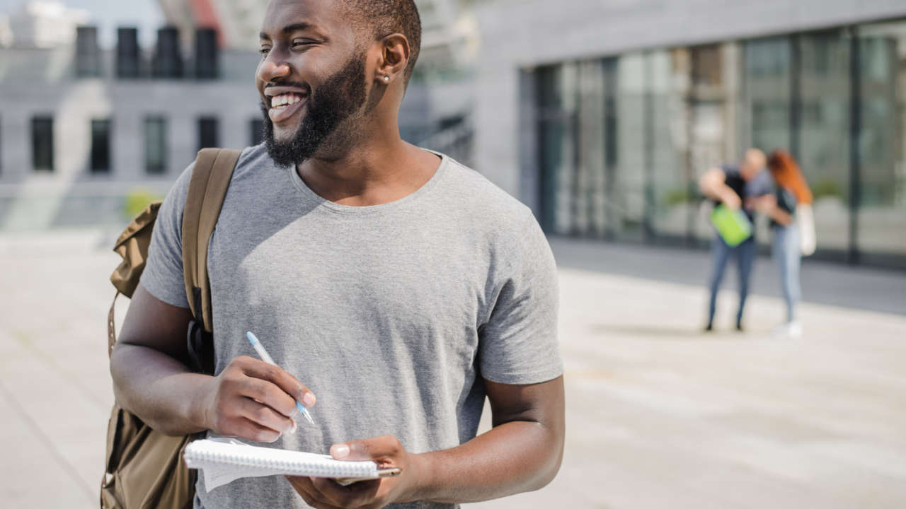 Jovem universitário negro com caderno na mão