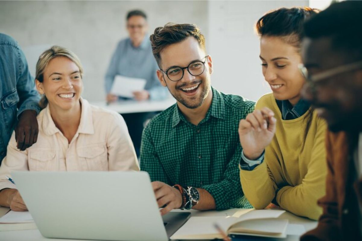 Um grupo com quatro estudantes conversa no refeitório em frente a um notebook onde consultam o Resultado do SISU 2025