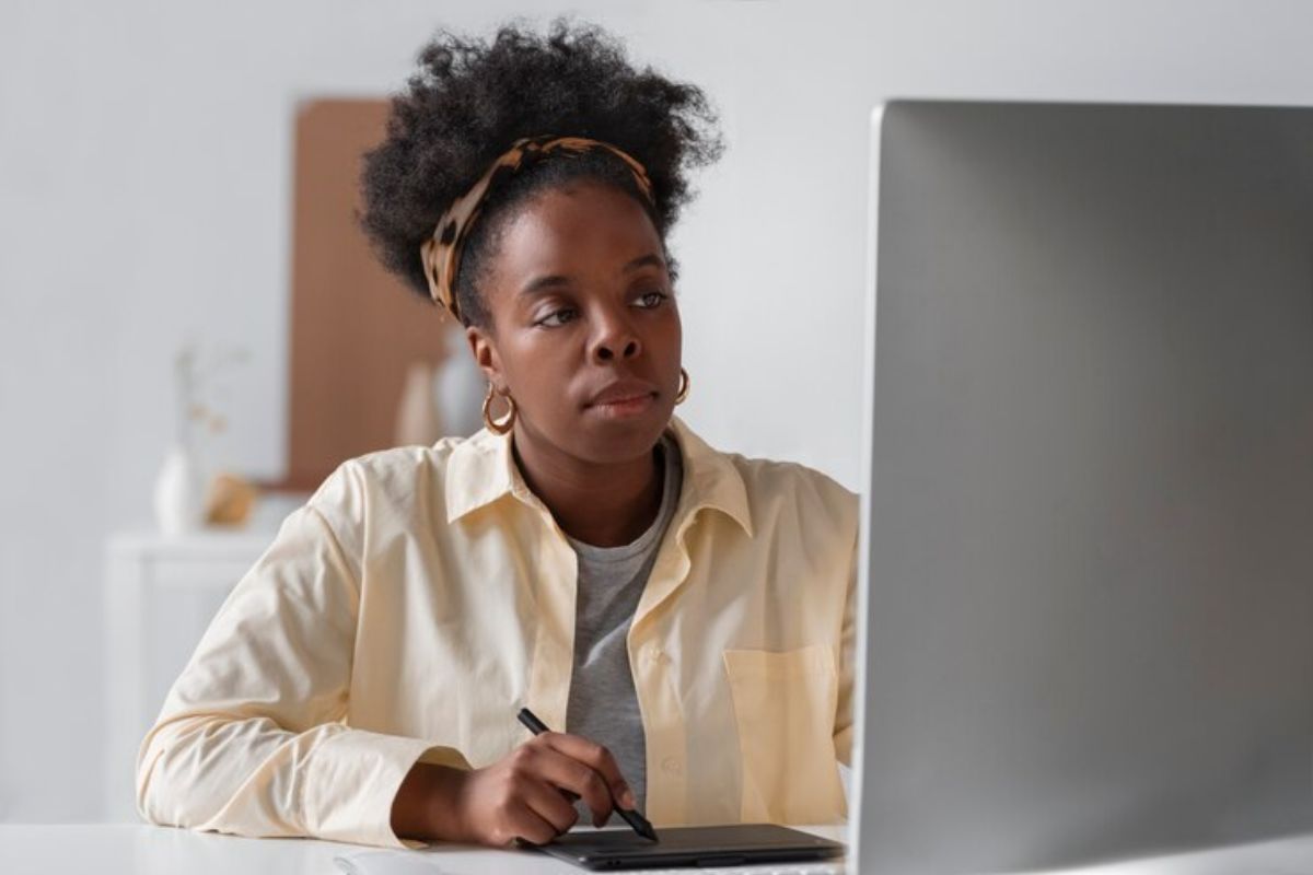 Uma estudante em casa usando o seu notebook que está na mesa