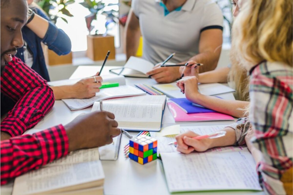 Um grupo de estudantes sentados em uma mesa estudando juntos