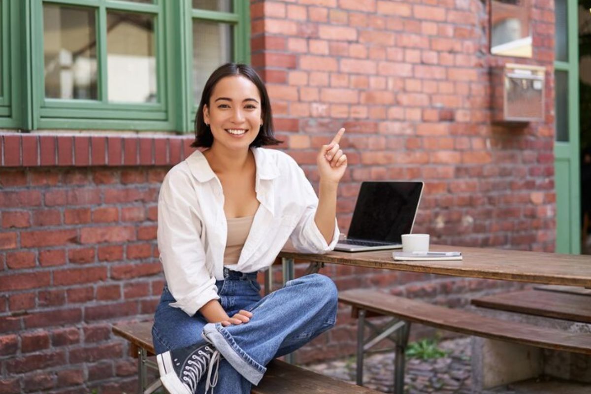 Uma estudante sentada. Na mesa em sua frente está seu notebook onde ela vê o Resultado do SISU 2025