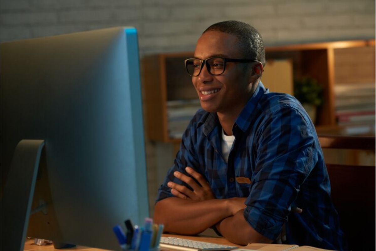 Um estudante em frente ao seu computador dentro do seu quarto